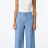 Wide-leg Tencel pants in light blue with relaxed drape and high-rise fit, photographed on a model wearing a white top in a bright neutral studio.