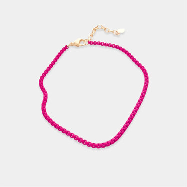 Pink beaded anklet with gold clasp on a light gray background
