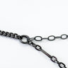 A black enamel necklace with a cuban chain design on a white background.