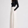 Side view of Rajasthan ivory high-rise wide-leg trousers styled with a fitted black top.