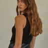 Regi Top side view of black sleeveless ribbed tank top with close fit silhouette.
