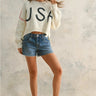 Full body view of Rope USA Knit Sweater in off white styled with denim shorts.