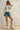 Full body view of Rope USA Knit Sweater in off white styled with denim shorts.