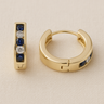 Sera Huggie Earrings, gold huggie hoop earrings with round stone inlay detail and polished mirror finish, photographed on white linen background with soft editorial lighting.
