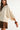 Side view of the Sienu Sweater in cream highlighting the flowing cape sleeves, relaxed silhouette, and soft knit texture.