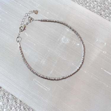 Silver disc bead bracelet with a sliding chain closure, displayed on a white surface.