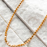 Stage Necklace by Matte, gold plated coin chain on textured white surface