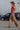 Woman in leopard print pants and pink top walking on a street.