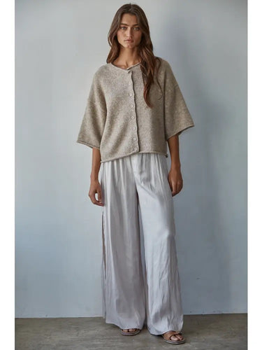 Talina lightweight knit cardigan featuring a button-front design, relaxed fit, and rolled-edge detailing, styled over a matching neutral outfit.