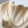 Teresina Necklace by Matte, gold filled tube chain on cream textured surface