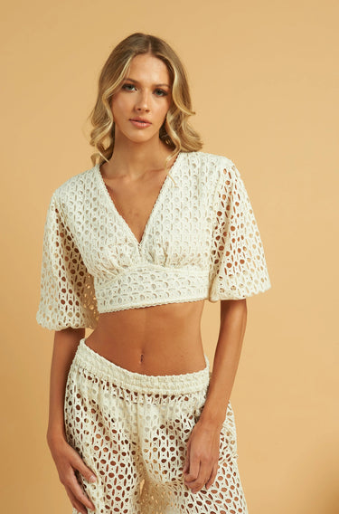 Model wearing the Tottem Crop Top in white — cotton eyelet fabric, cropped silhouette, V-neck, wide sleeves, close up.