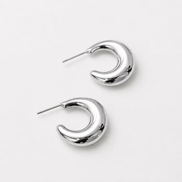 Turnhout Hoop Earrings featuring polished silver-plated sculptural hoop earrings with a twisted C-shaped silhouette, smooth mirror finish, lightweight hollow design, secure post-back closure, and modern statement style.