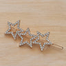Gold triple star hair clip with crystal accents on wood background – Ventura Hair Clip by Matte.