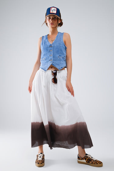 Woman wearing a denim vest, white and brown gradient skirt, and leopard print shoes on a light gray background