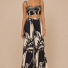 Woman wearing the Vittoria Set featuring a black and ivory abstract print, adjustable tie-shoulder cropped top, high-waisted wide-leg pants, lightweight woven fabric, and a relaxed resort-inspired silhouette.