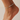 white anklet with a small charm on a foot against a neutral background