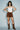 Front view of model wearing the Yagu Skirt featuring a suede-look finish, western-inspired stud detailing, mini silhouette, and buckle waistband.