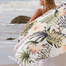 Yatay Multi Wear Wrap with tropical botanical print and tassel trim at the beach.
